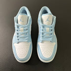 Pair of light blue and cream low-top sneakers with laces and perforated toe