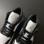 Pair of low-top sneakers showing tongues and heel counters with black laces and light blue Jumpman.