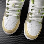 Low-top sneaker front with perforated white leather and neon green lace accents