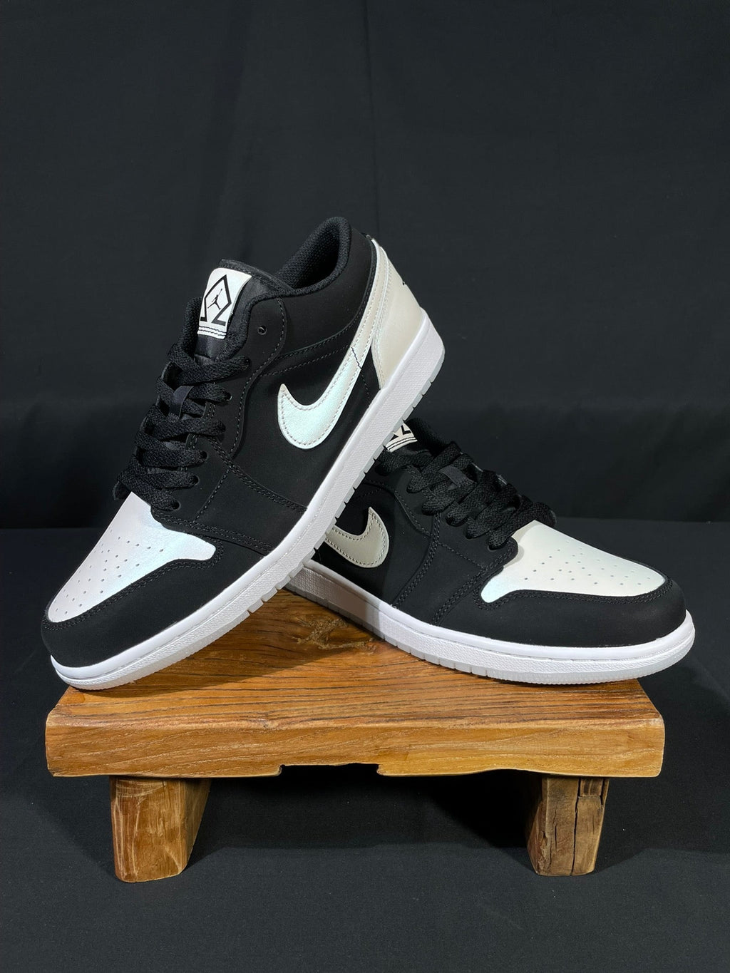 Pair of black and white low-top sneakers on stand, white midsoles, lace-up design