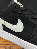 Black low-top sneaker side with white Nike swoosh and textured stitching detail