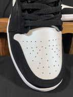 Black and white low-top sneaker toe with perforations, black laces, and curved sole