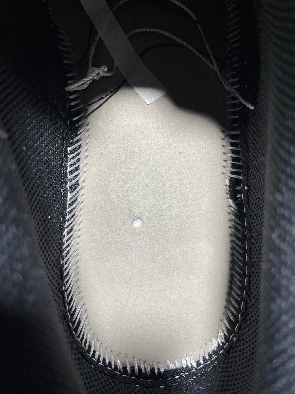 Black low-top sneaker interior with white padded insole and stitched edge