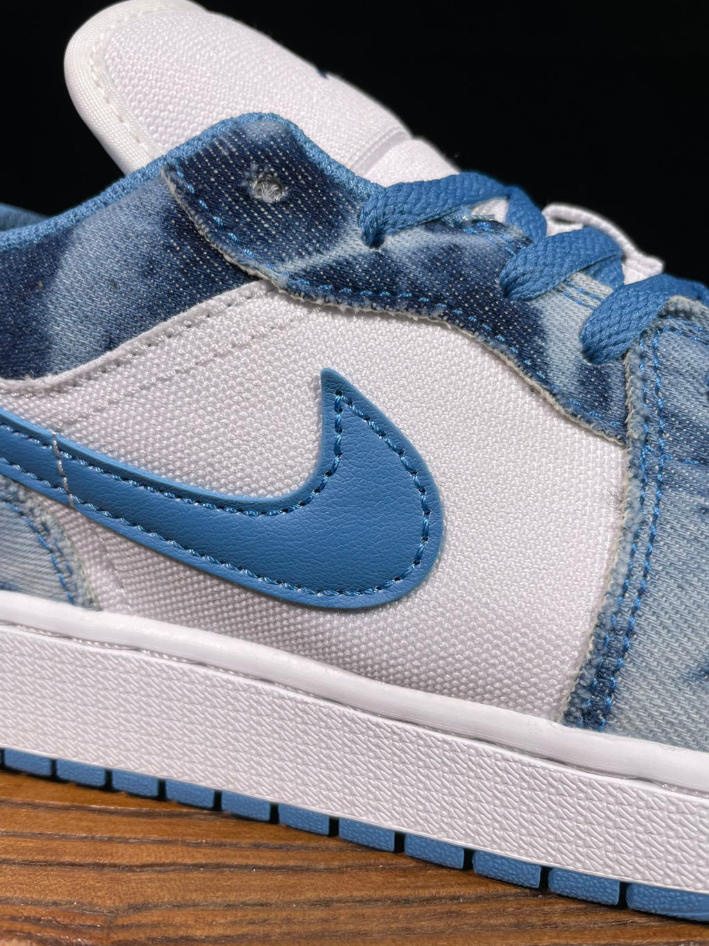 Air Jordan 1 Low sneaker close-up of blue Swoosh and denim-washed overlays