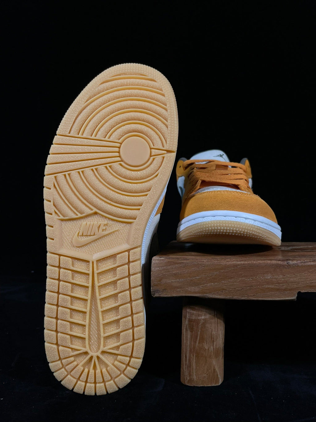 White rubber outsole of orange low-top sneakers with Nike logo on heel.