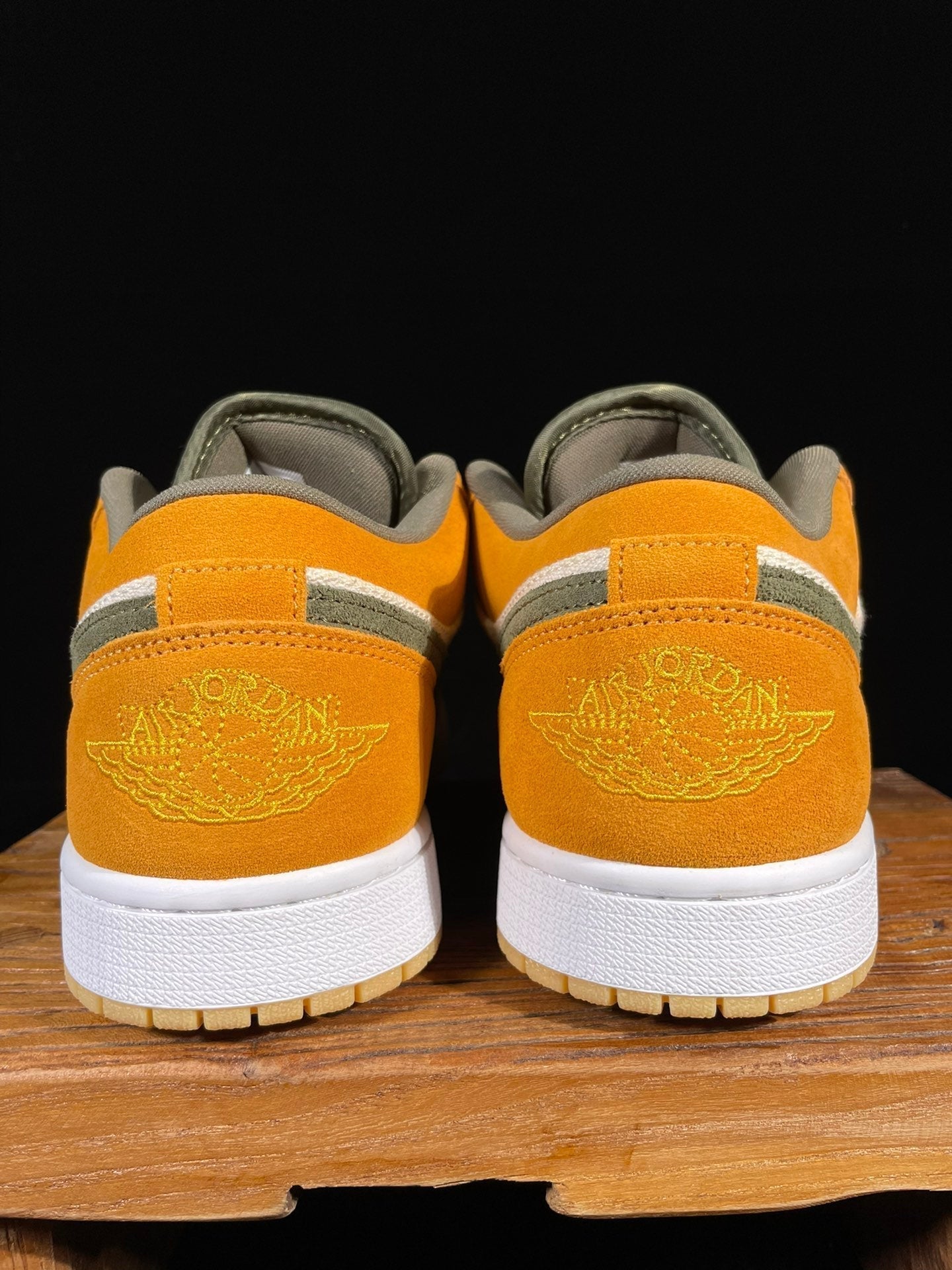 Rear view of orange low-top sneakers with white heel panels and olive accents.