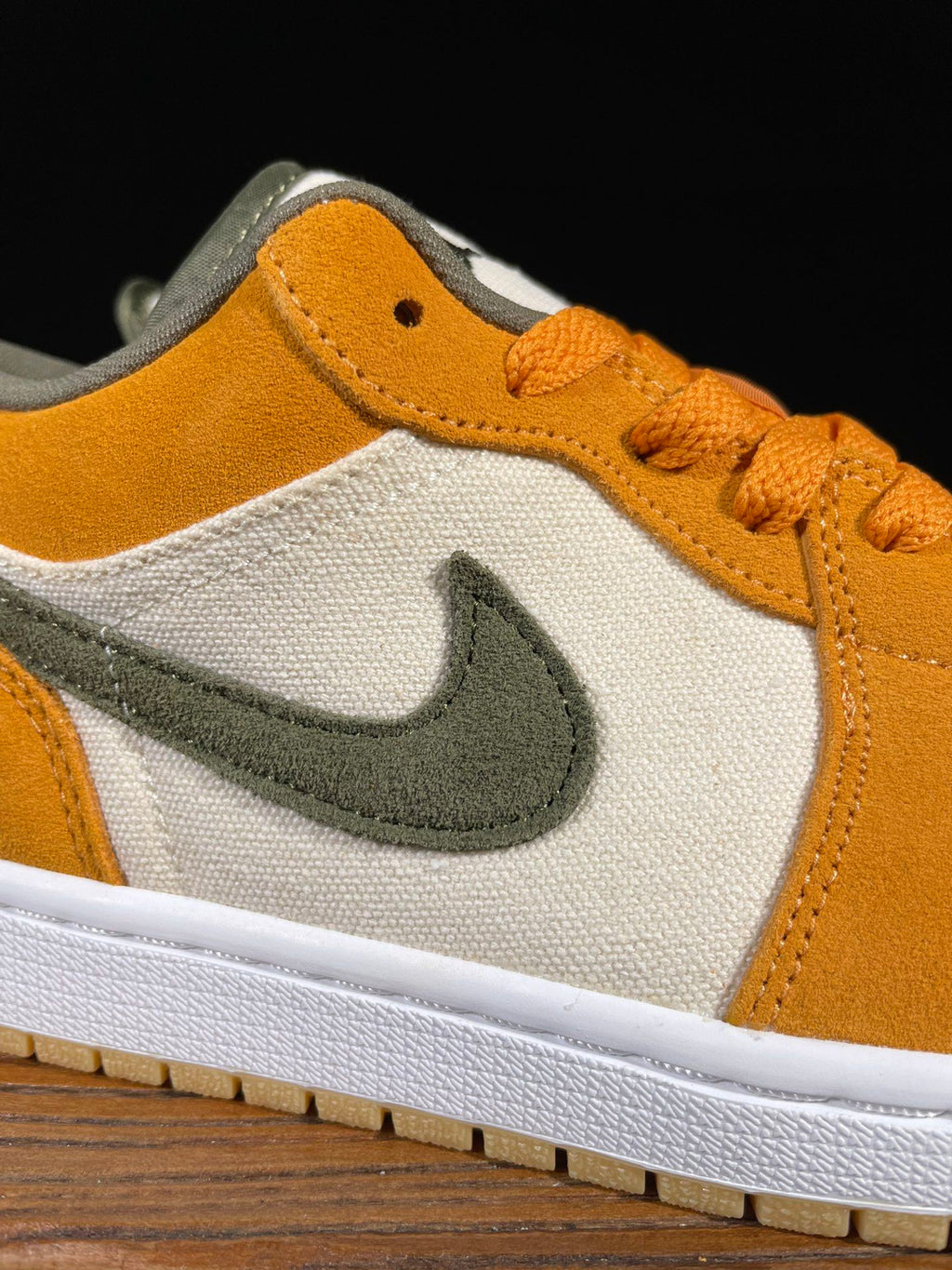 Orange suede and white low-top sneakers with olive Nike swoosh and orange laces.