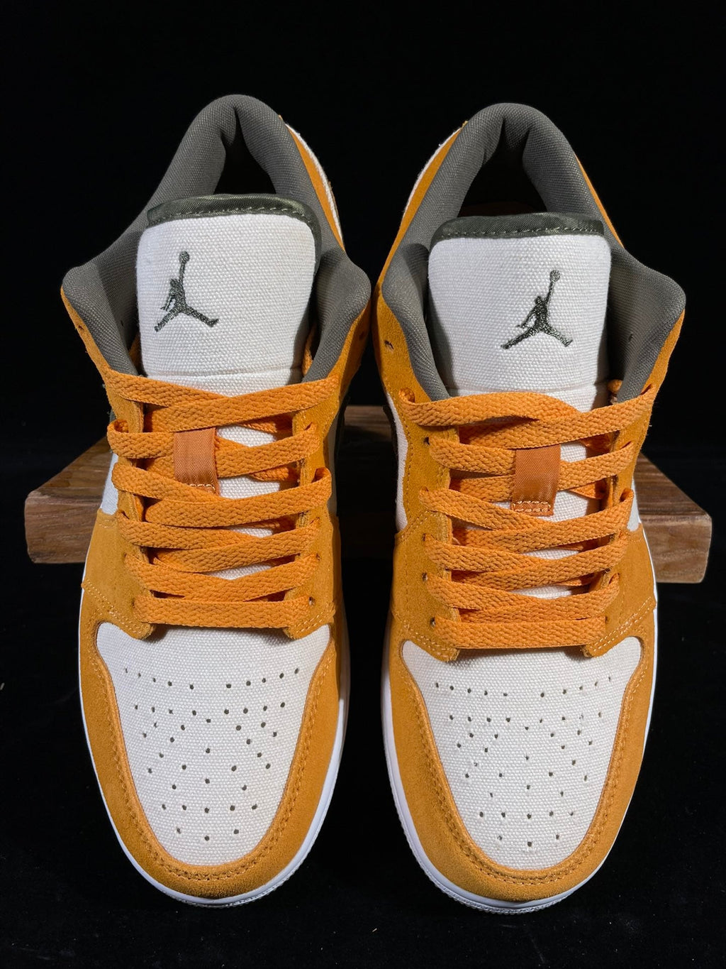 Orange and white low-top sneakers with black Jordan logo on tongue; lace-up style.