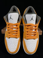 Orange and white low-top sneakers with black Jordan logo on tongue; lace-up style.