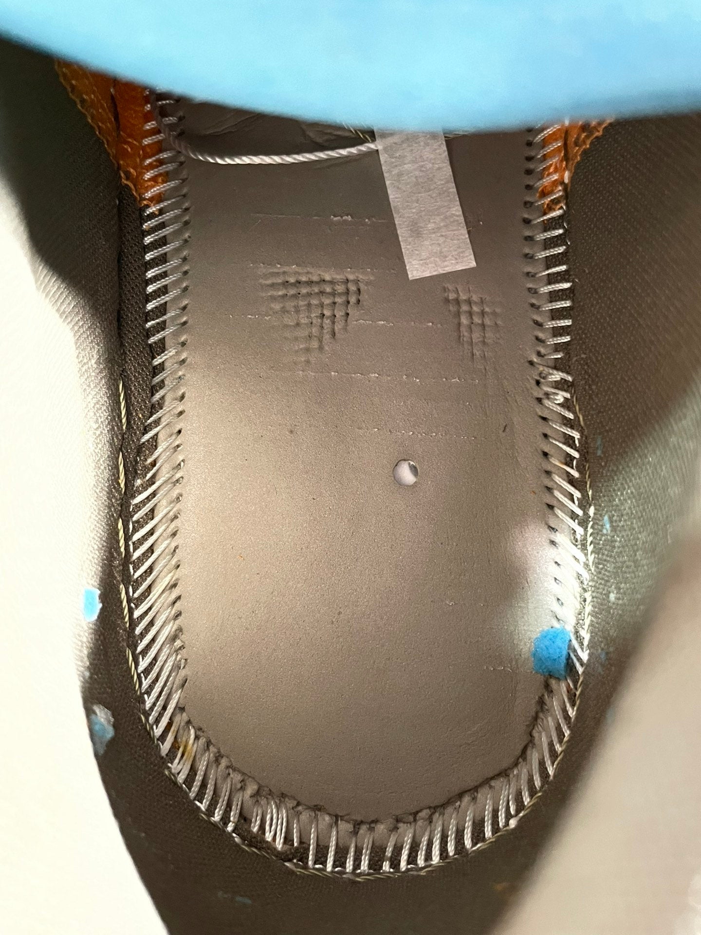 Low-top sneaker interior lining with stitched seam and small blue adhesive marks.