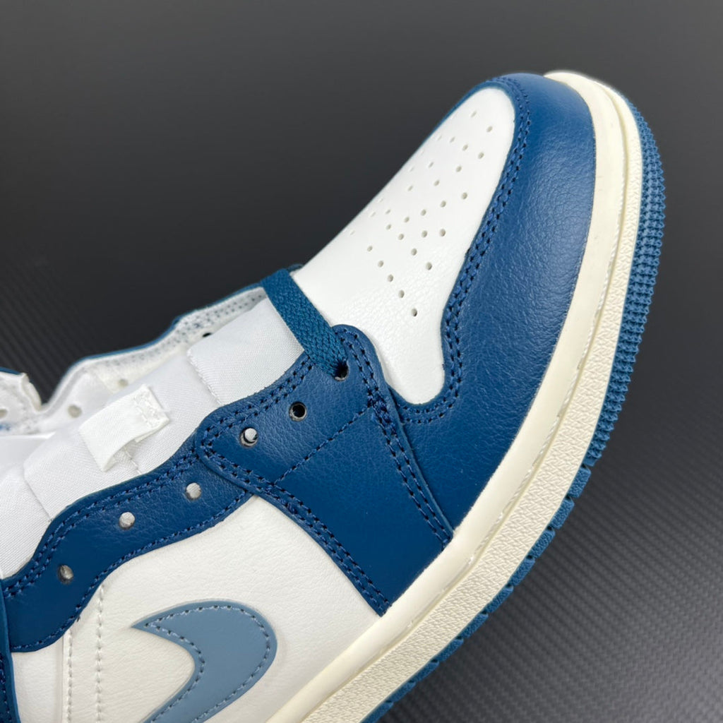 Mid-top sneaker upper close-up with blue and white leather panels and lace eyelets.