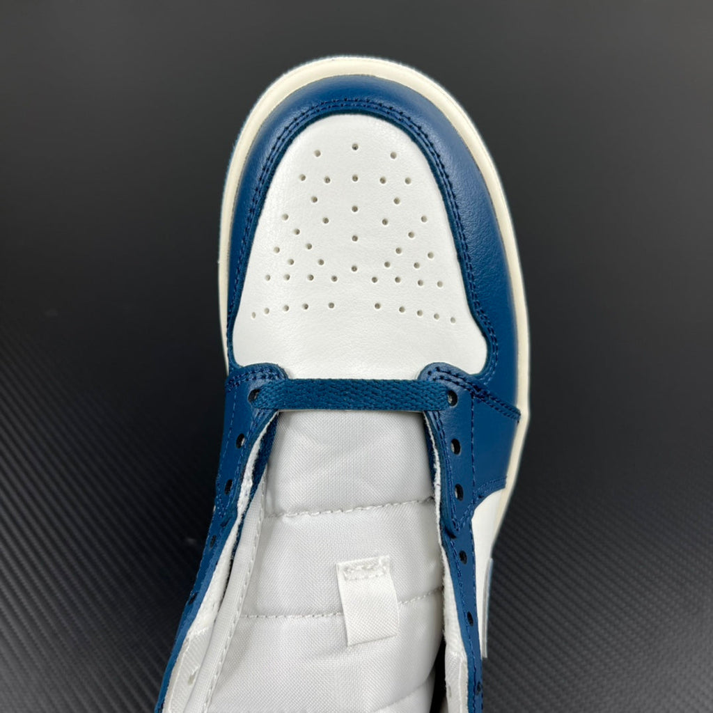 Mid-top sneaker toe box view with perforations, white laces, and blue leather overlays.