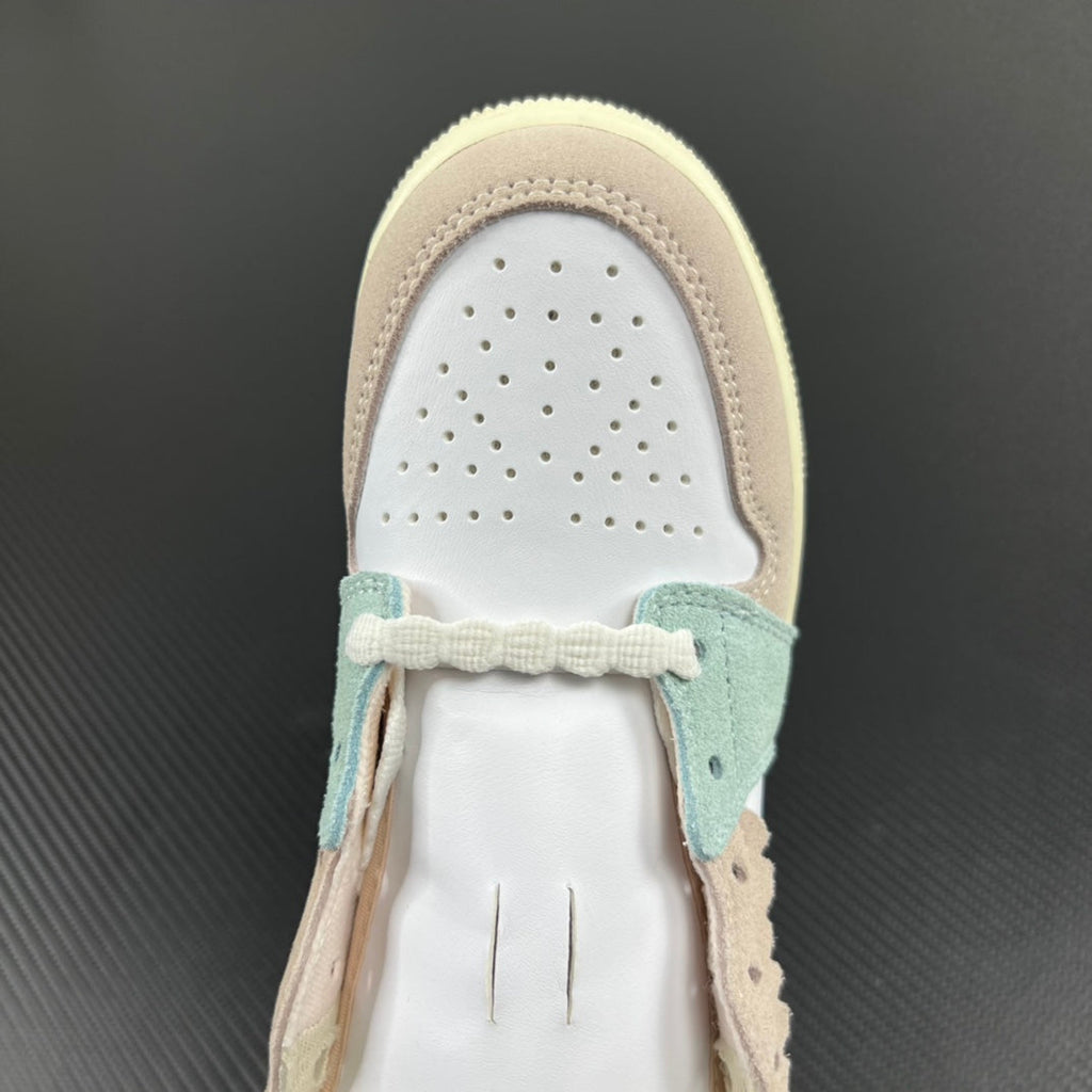 Air Jordan 1 Mid sneaker toe box view with perforations, beige trim, and mint lace detail