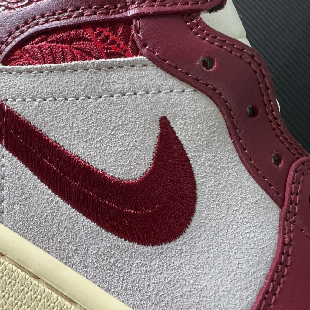 Close-up of white leather side panel with burgundy Nike swoosh and burgundy stitching