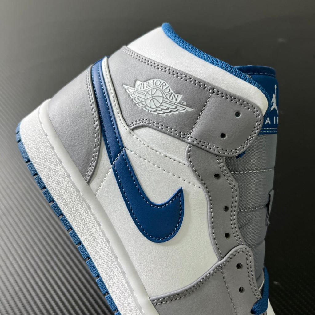 Mid-top sneaker side view with wing logo patch and blue swoosh accents