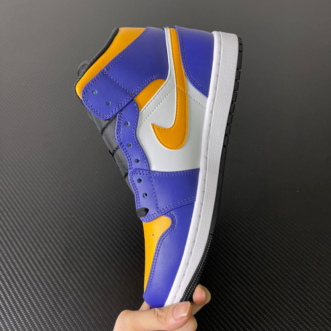 Mid-top sneakers held in hand, purple upper with yellow toe, white swoosh, black outsole