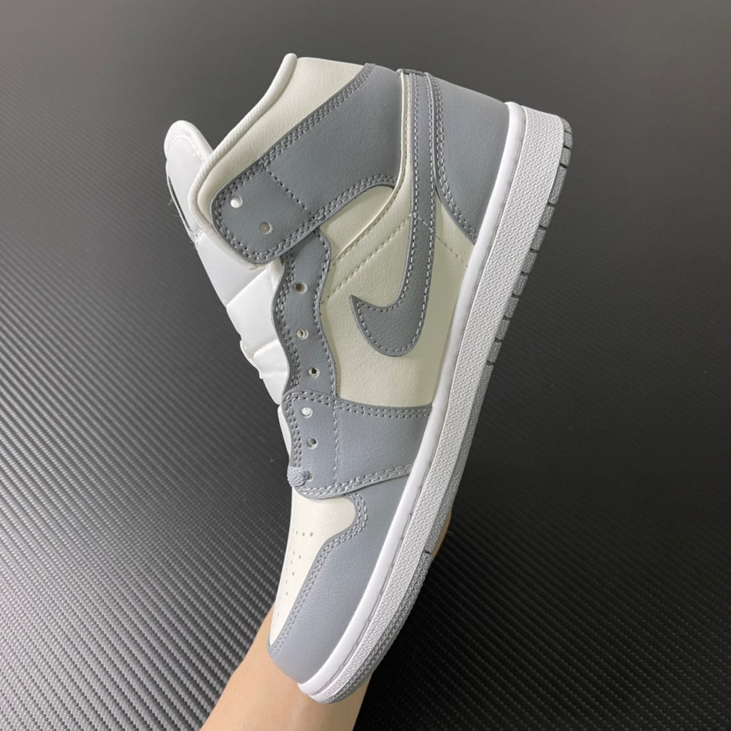 Air Jordan 1 Mid sneaker 3/4 view with light grey strap and sail base