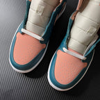 Air Jordan 1 Mid pair close-up at vamp and ankle, teal blue leather with peach toe panel.