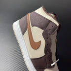 Mid-top Air Jordan 1 side view, cream toe with dark brown collar and tan strap detail