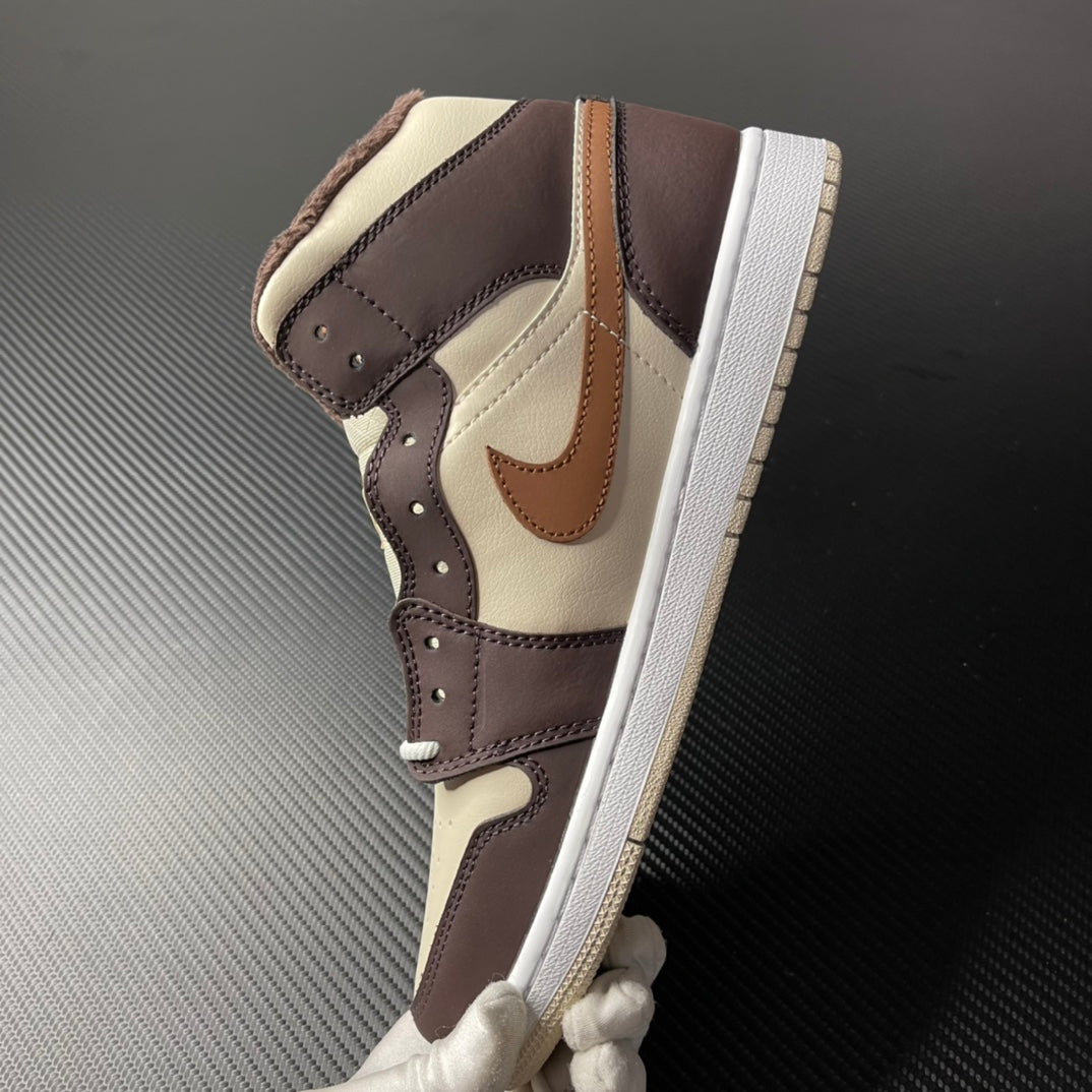 Mid-top Air Jordan 1 shoe with cream base, dark brown panels and tan swoosh on side