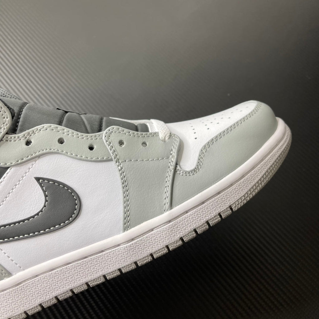 White and light gray mid-top sneaker with black swoosh and lace eyelets