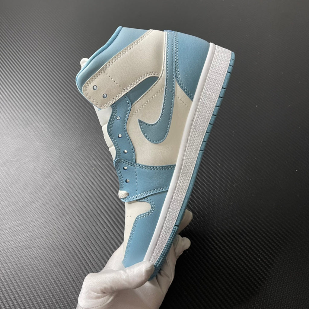 Jordan 1 Mid high-top sneakers in white and light blue, showing side panels and striped outsole