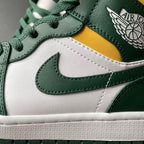 Mid-top sneakers close-up: green swoosh on white leather with yellow stripe.