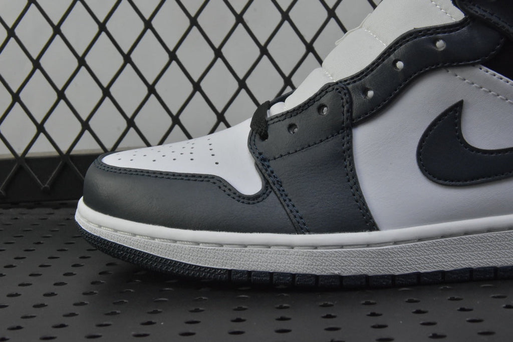 Close-up side of mid-top sneakers with white leather panels and dark teal swoosh