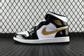 Air Jordan 1 Mid sneakers, black and white with gold swoosh, lace-up mid-top
