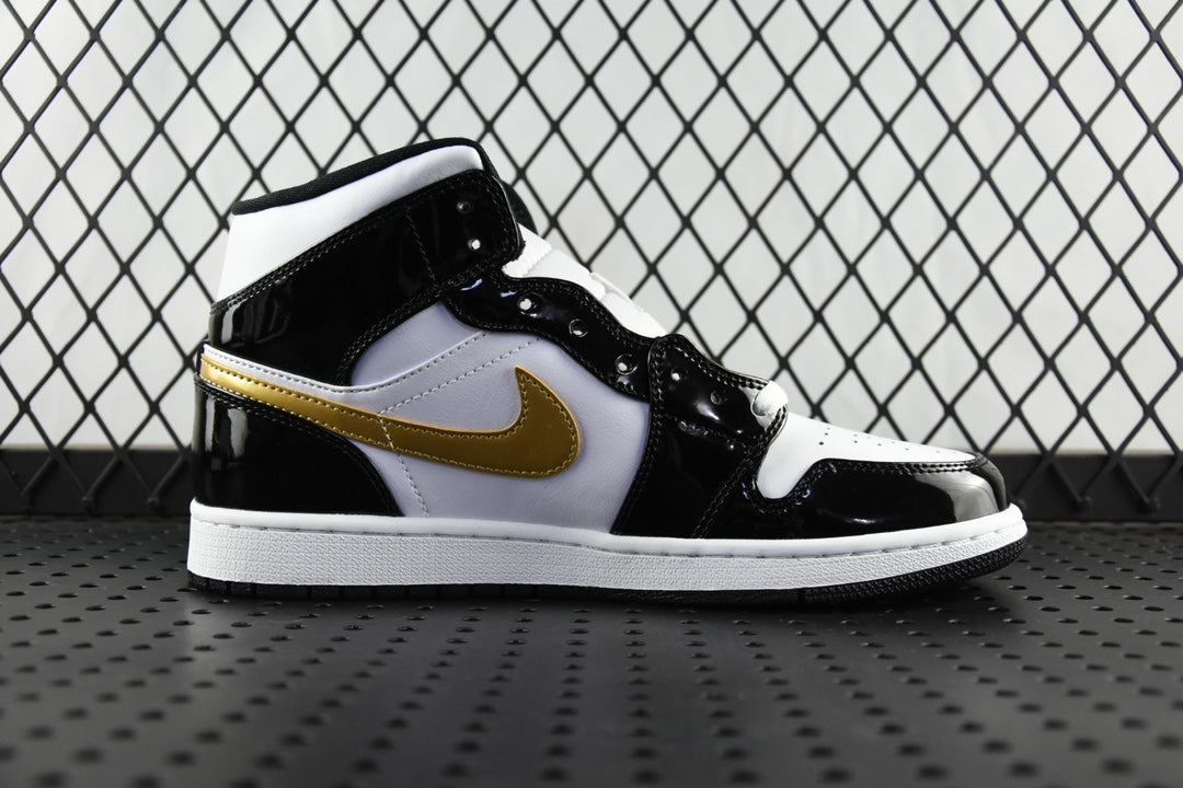 Air Jordan 1 Mid sneaker, black and white leather with gold swoosh, side profile