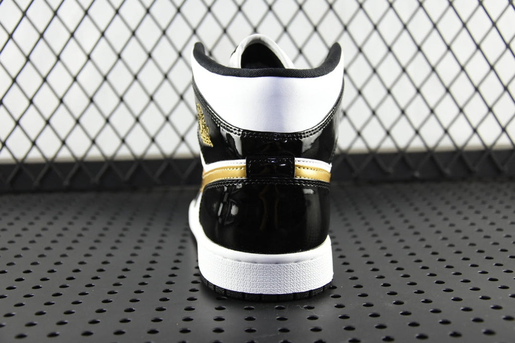 Air Jordan 1 Mid sneaker heel view, black upper with gold stripe and white sole