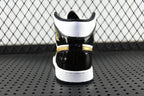 Air Jordan 1 Mid sneaker heel view, black upper with gold stripe and white sole