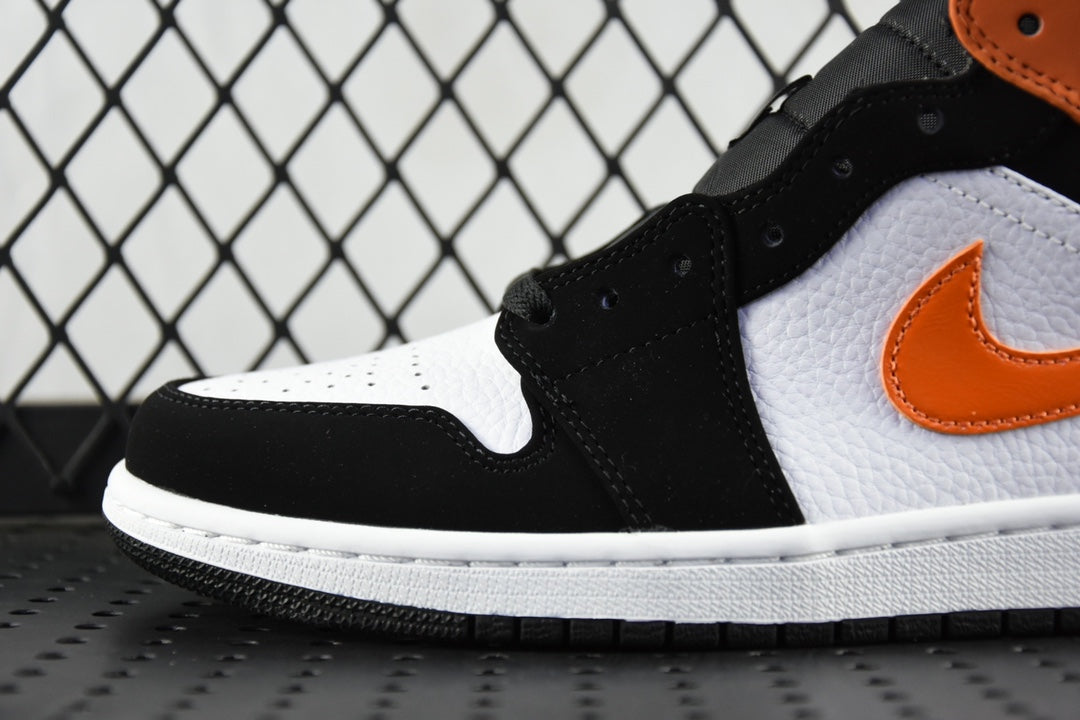 Air Jordan 1 Mid sneakers close-up with black upper, white toe panel, orange swoosh