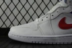 White leather sneaker with red swoosh and blue trim stitching near toe.