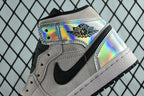 Air Jordan 1 Mid sneaker close-up, iridescent lace strap with black swoosh on gray suede