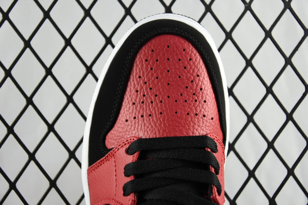Close-up of red perforated toe box on black and red mid-top sneaker