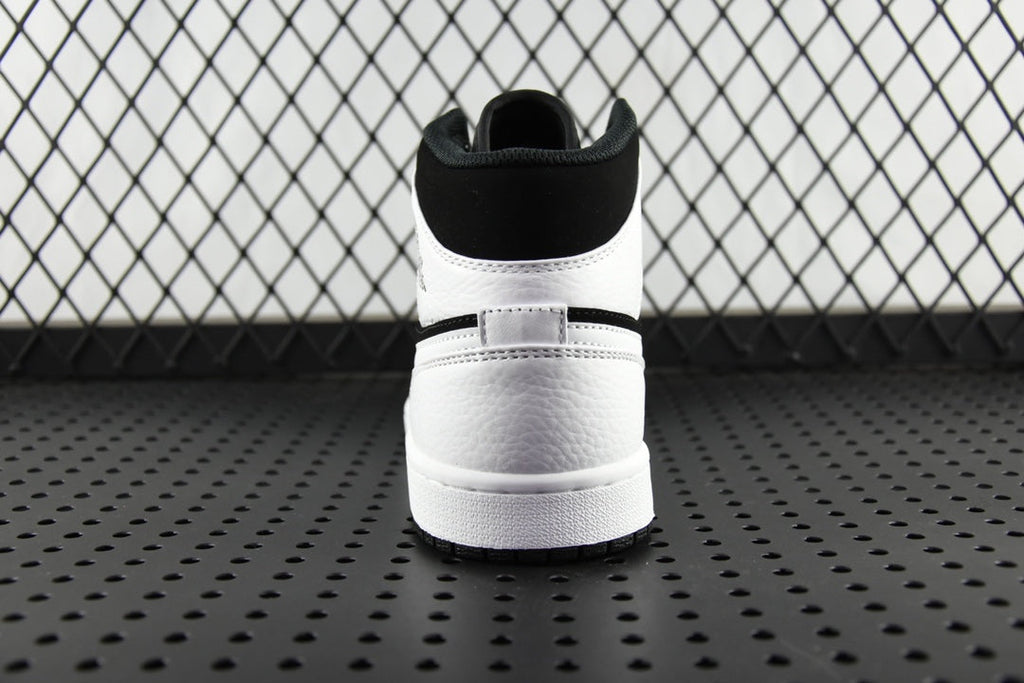 Black and white mid-top sneakers, rear collar and rubber heel sole