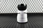 Black and white mid-top sneakers, rear collar and rubber heel sole