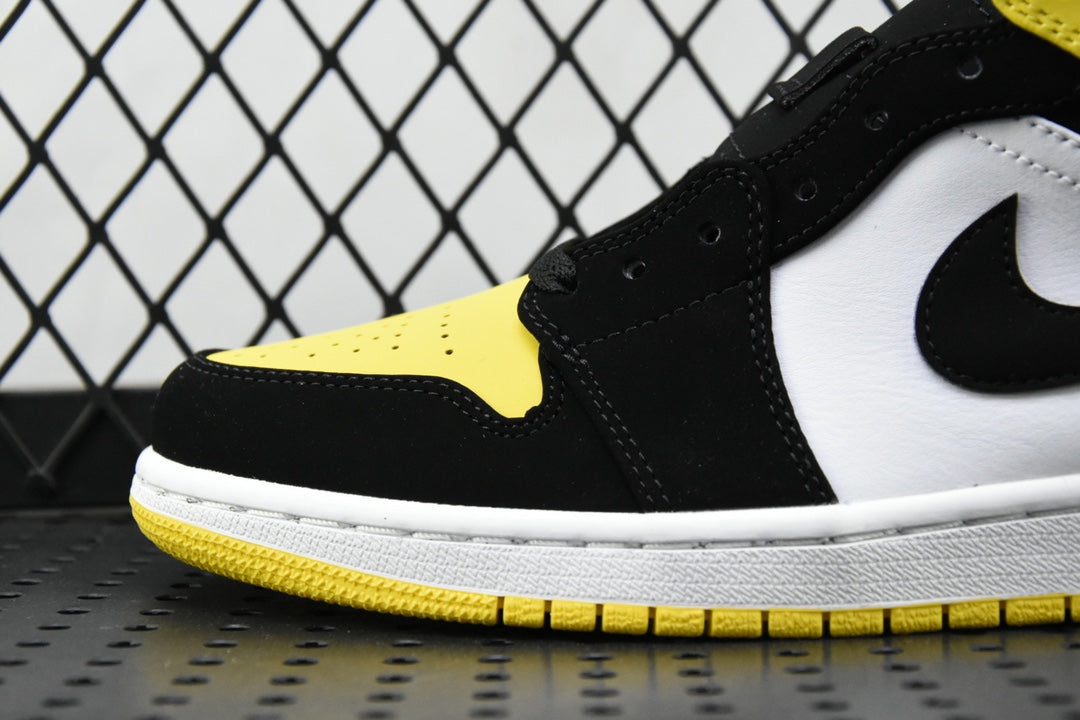 Air Jordan sneaker close-up of toe box in black and yellow with white swoosh