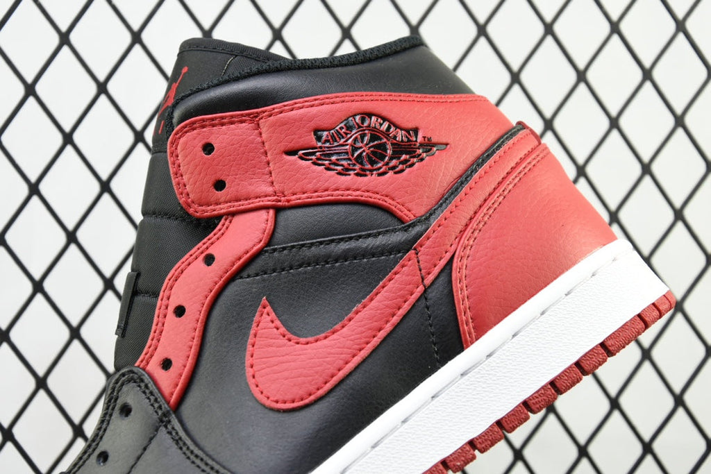 Heel and side view of mid-top sneaker with red ankle panel and black leather