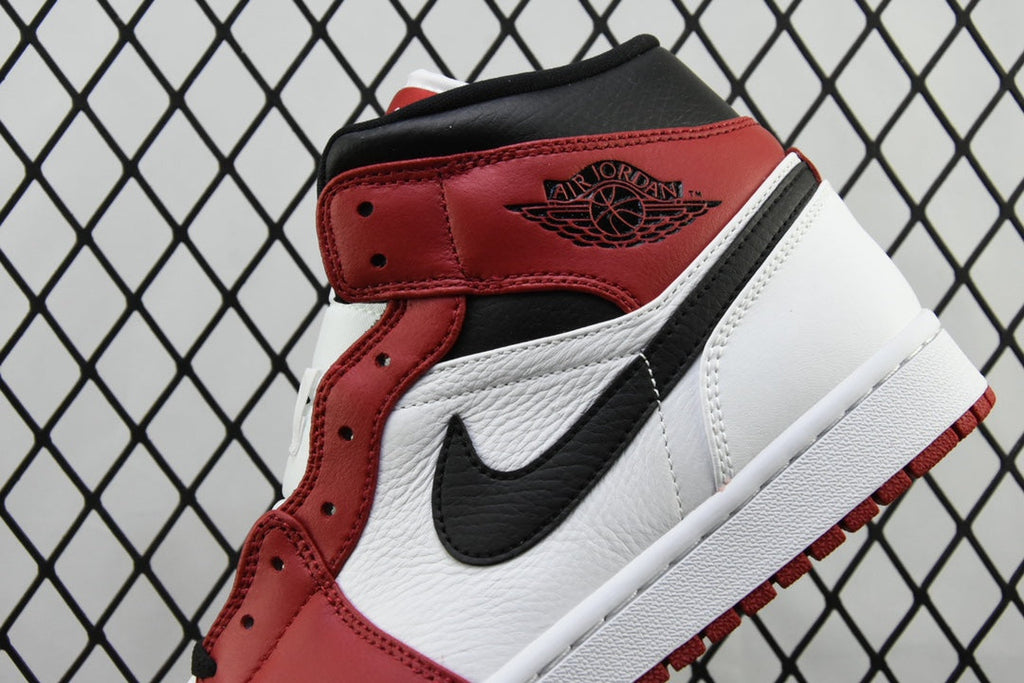 Close-up mid-top sneaker quarter panel with black swoosh and red leather strap