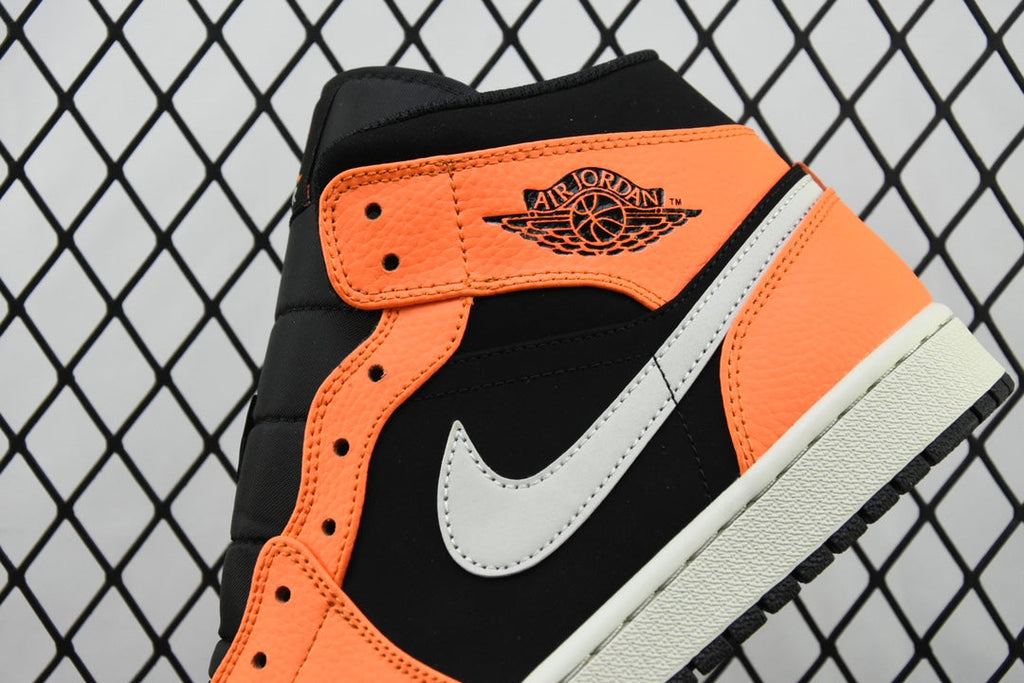 Front quarter view of mid-top sneakers with black upper, orange accents, and white swoosh