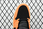 Toe box view of mid-top sneaker with orange interior, black laces, and perforated toe