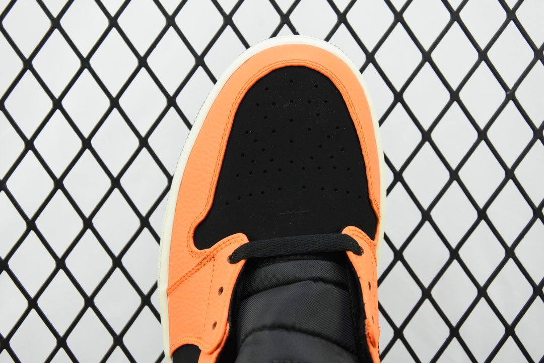 Toe box view of mid-top sneaker with orange interior, black laces, and perforated toe