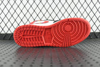Red rubber outsole of mid-top sneakers with grid tread and center logo