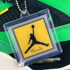 Clear charm with yellow Manila Jumpman logo attached to a metal chain