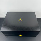 Dark shoe box lid with neon Manila Jumpman logo and yellow accent label