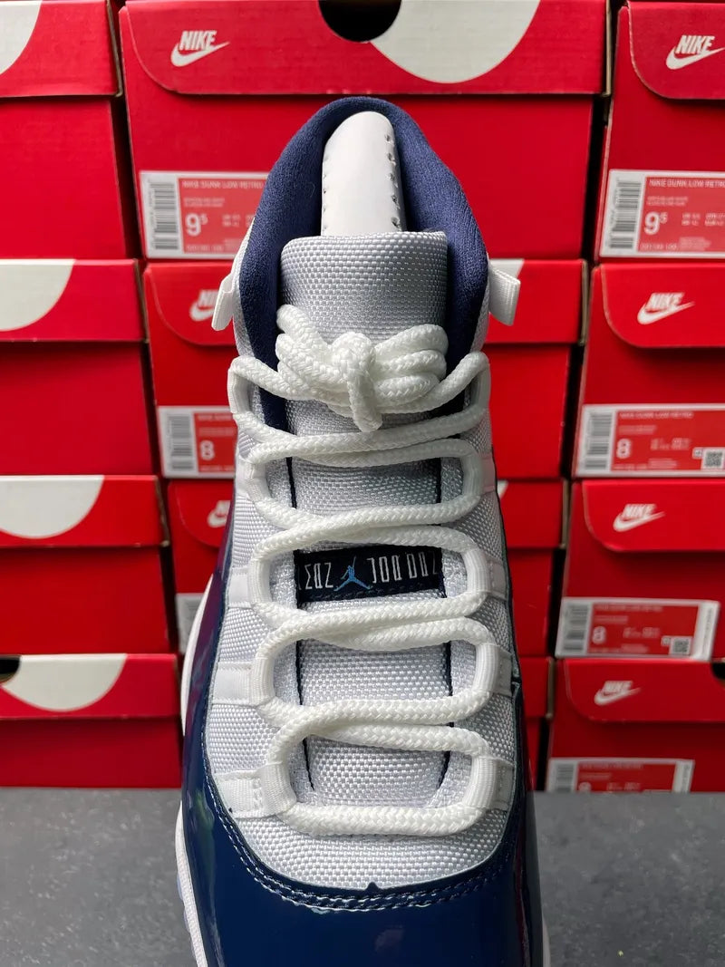 Air Jordan 11 sneakers with white mesh upper, navy side panel, and lace-up front