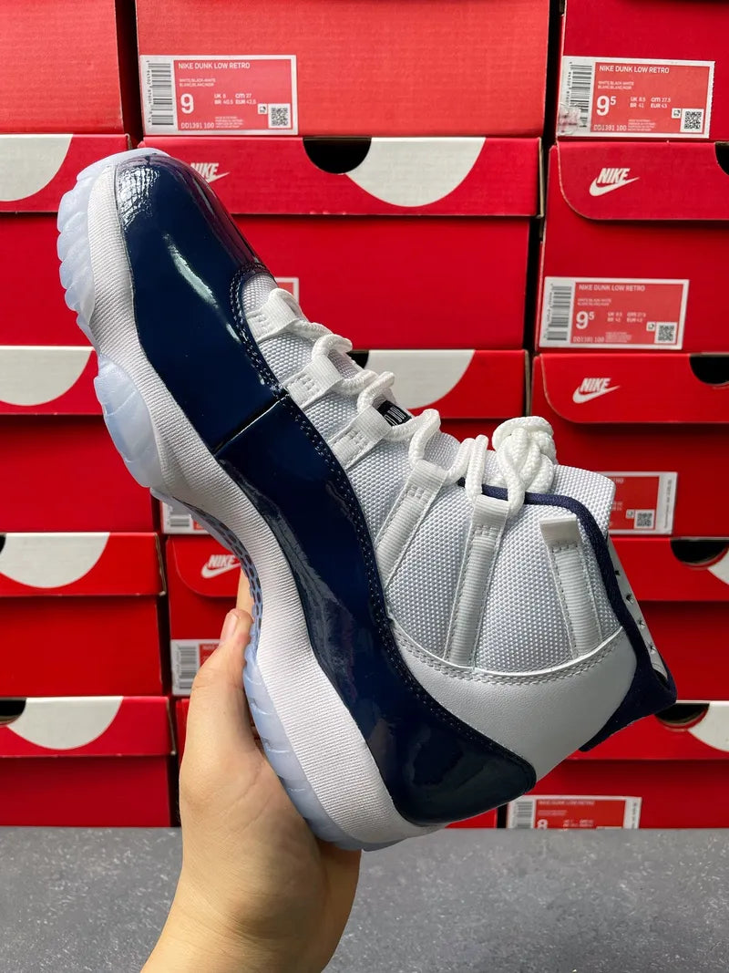 Air Jordan 11 sneakers angled side view with white mesh and glossy navy panels