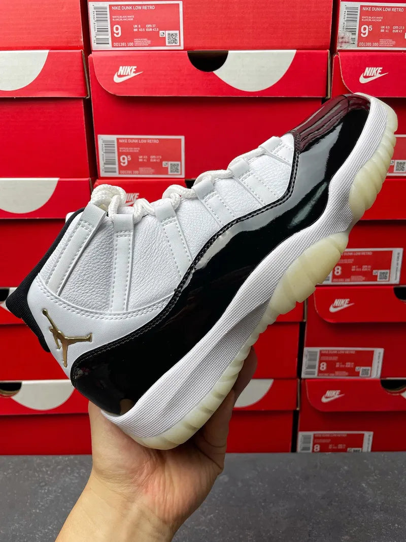 White and black Air Jordan 11 high-top sneaker, side view with gold logo detail